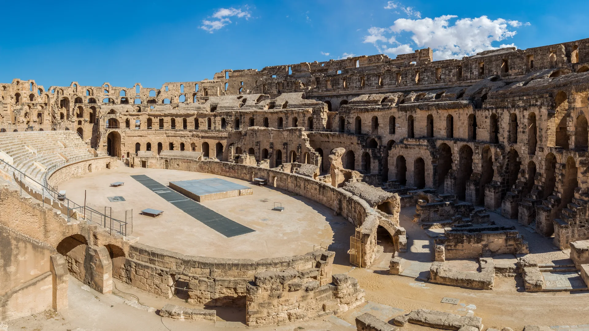 The great Roman amphitheatre of El Jem in golden stone under a blue sky
